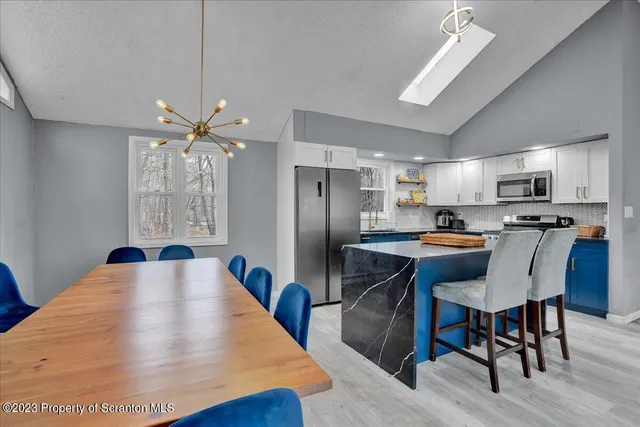 a kitchen with stainless steel appliances kitchen island granite countertop a table chairs refrigerator and microwave