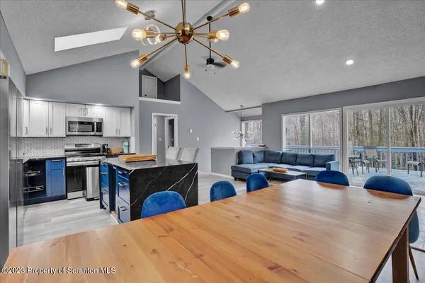 a kitchen with stainless steel appliances kitchen island granite countertop a refrigerator a stove a sink dishwasher a dining table and chairs with wooden floor