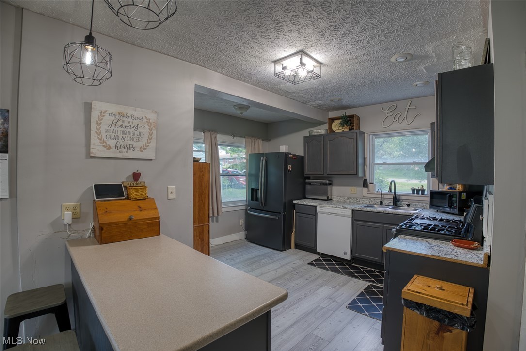 2161 Canton Road Akron, OH 44312 - Photo 13 of 33 Kitchen featuring black appliances, a peninsula, light wood-style flooring, light countertops, and a textured ceiling