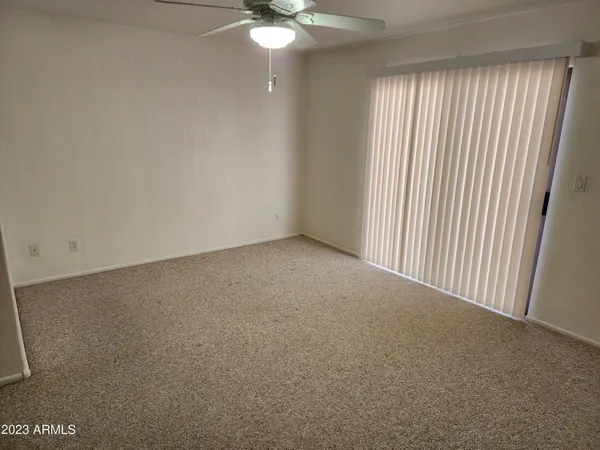 an empty room with windows and fan