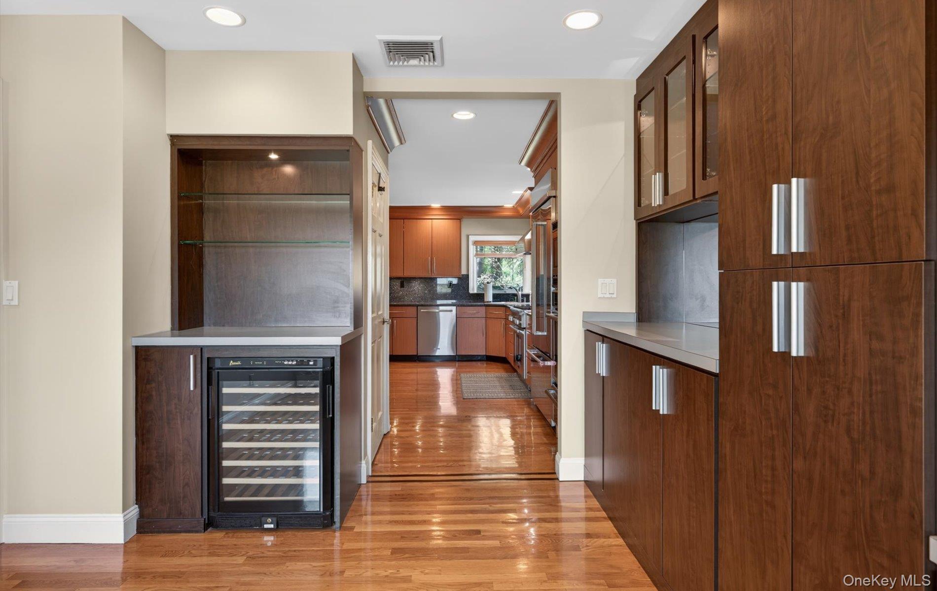 16 East Slope Road Bayville, NY 11709 - Photo 17 of 48 Built-in beverage cooler with glass shelving, wood-finish flooring, recessed lighting, and extensive cabinetry with modern hardware