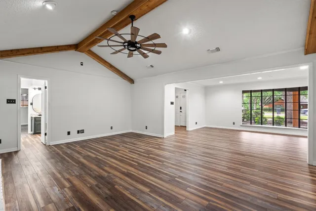 a view of an empty room with a window and wooden floor