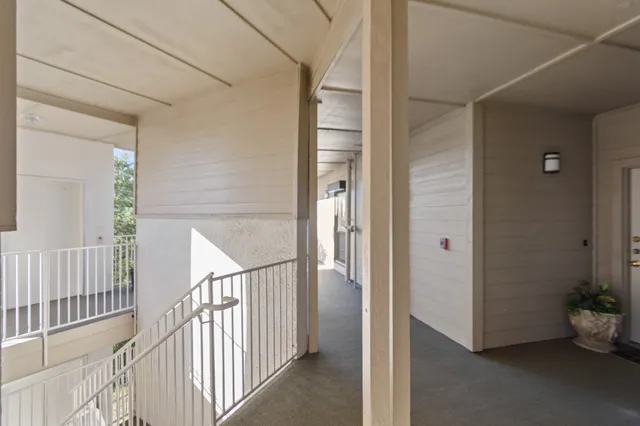 a view of a hallway to a room with wooden floor and stairs