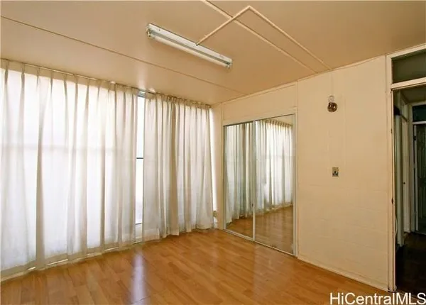an empty room with wooden floor and windows with curtains