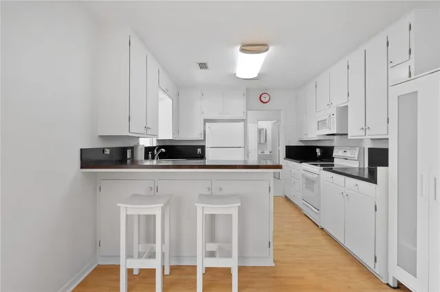 a kitchen with granite countertop white cabinets and white appliances