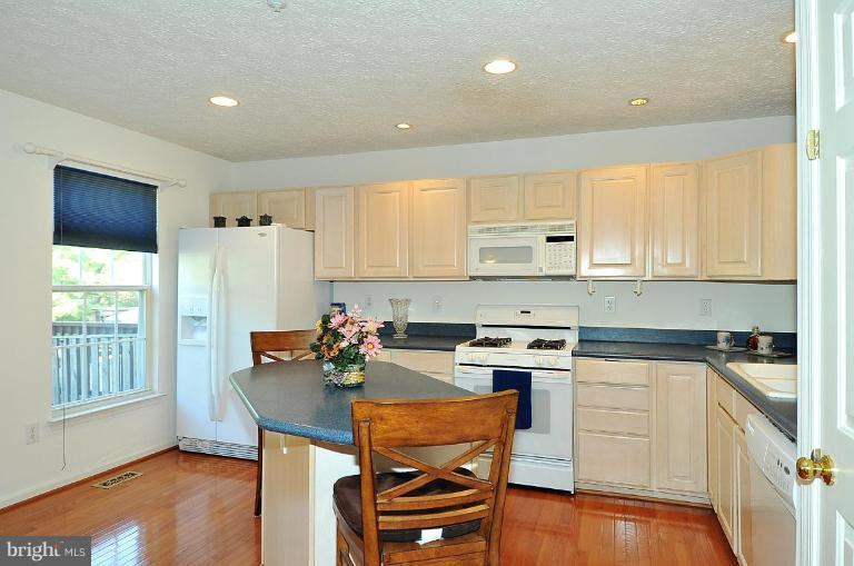 6116 Starburn Path Columbia, MD 21045 - Photo 17 of 18 a kitchen with stainless steel appliances granite countertop a stove a sink dishwasher and a refrigerator with wooden floor