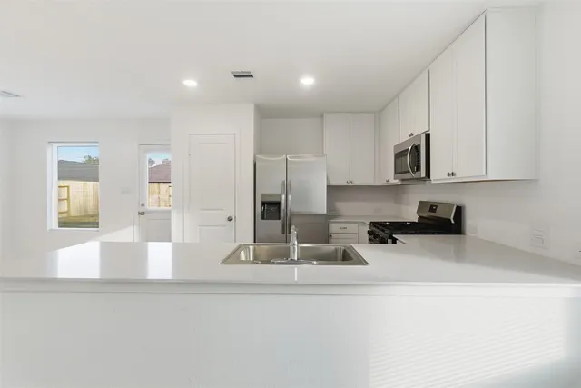 a kitchen with stainless steel appliances granite countertop a sink a stove and a refrigerator