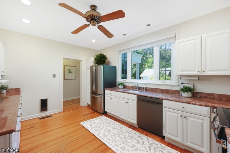 15 Georgian Road Morristown, NJ 07960 - Photo 12 of 44 a kitchen with stainless steel appliances granite countertop a refrigerator a sink dishwasher a stove and white countertops with wooden floor