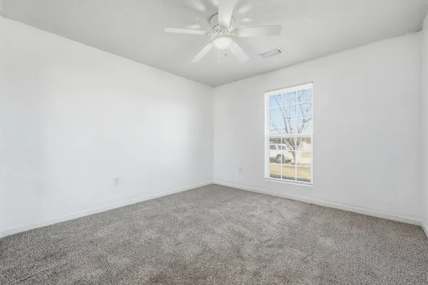 an empty room with windows and fan