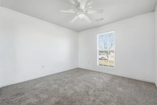 an empty room with windows and fan
