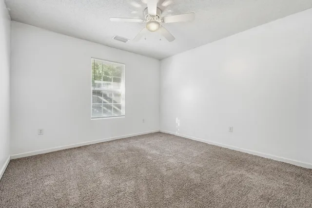 an empty room with windows and fan