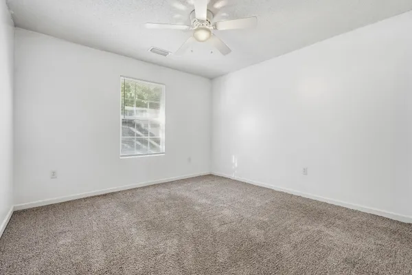 an empty room with windows and fan