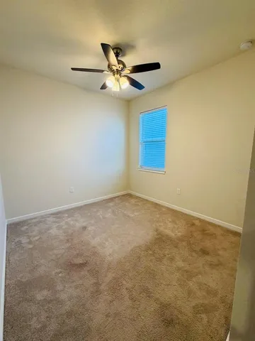 an empty room with a window and a ceiling fan