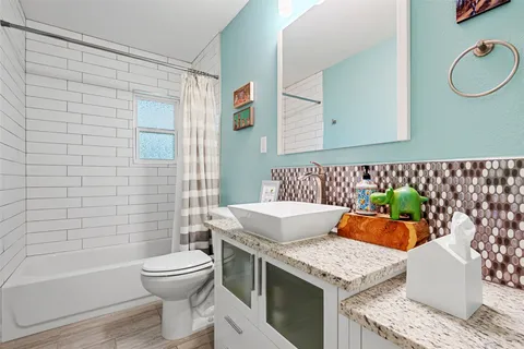 a bathroom with a granite countertop sink mirror vanity and toilet