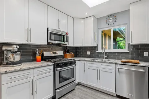 a kitchen with stainless steel appliances granite countertop a sink a stove and cabinets