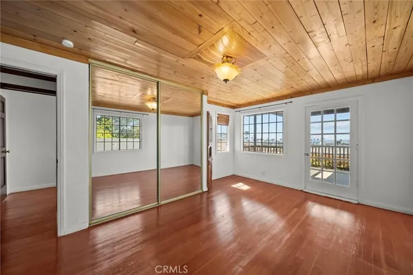 a view of empty room with wooden floor and a window