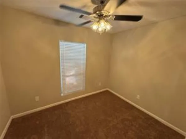 an empty room with a window and a fan