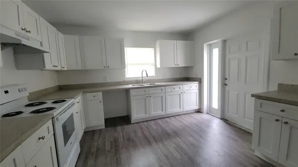 a kitchen with granite countertop a sink a stove cabinets and wooden floor