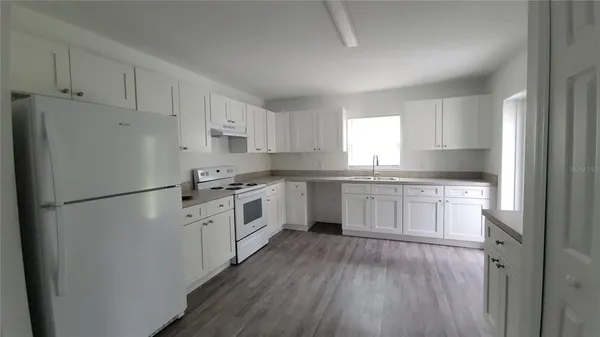 a kitchen with white cabinets white appliances and sink