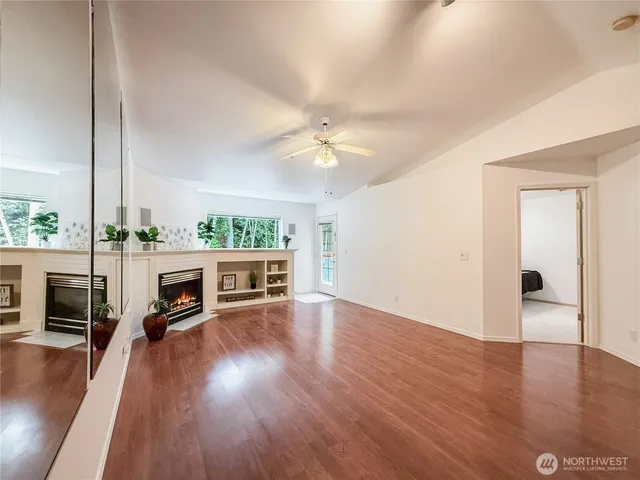 an empty room with wooden floor fireplace and windows