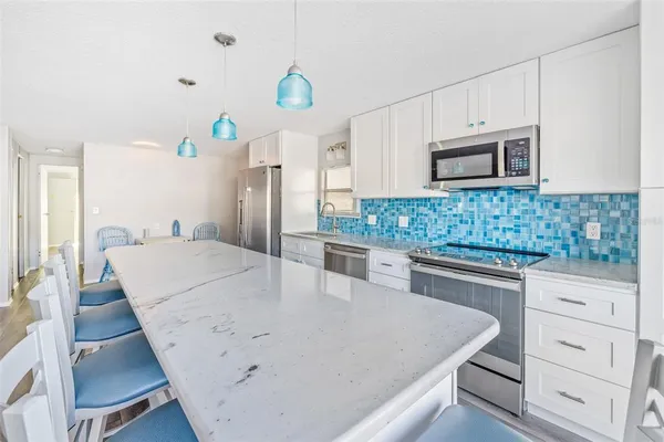 a kitchen with kitchen island a counter top space a sink stainless steel appliances and cabinets