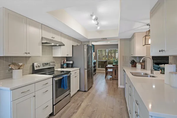 a kitchen with white cabinets appliances and sink