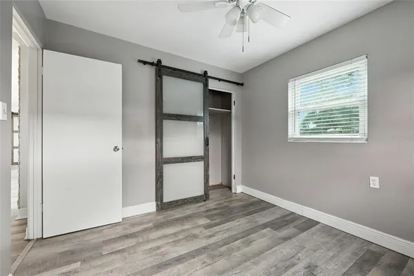 a view of empty room with wooden floor and fan