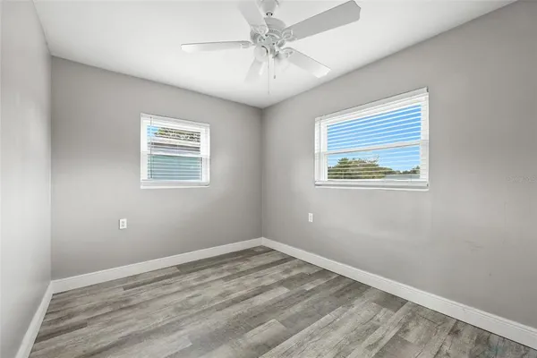 a view of empty room with wooden floor and fan