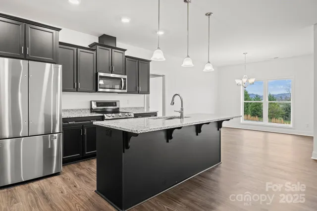 a kitchen with stainless steel appliances granite countertop a sink a stove and a refrigerator