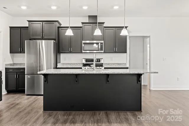a kitchen with stainless steel appliances granite countertop a stove a refrigerator and a sink