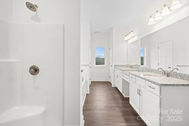 a spacious bathroom with a granite countertop sink a mirror and a bathtub