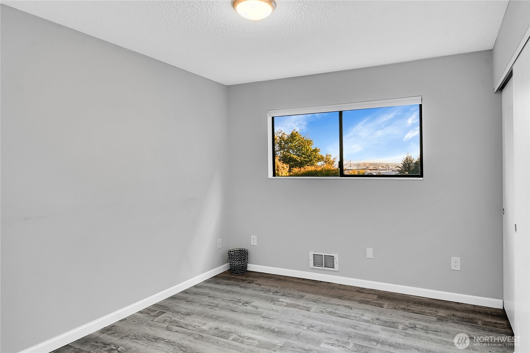 2562 Thorndyke Avenue West, Unit 104 Seattle, WA 98199 - Photo 13 of 18 a view of an empty room with wooden floor and windows