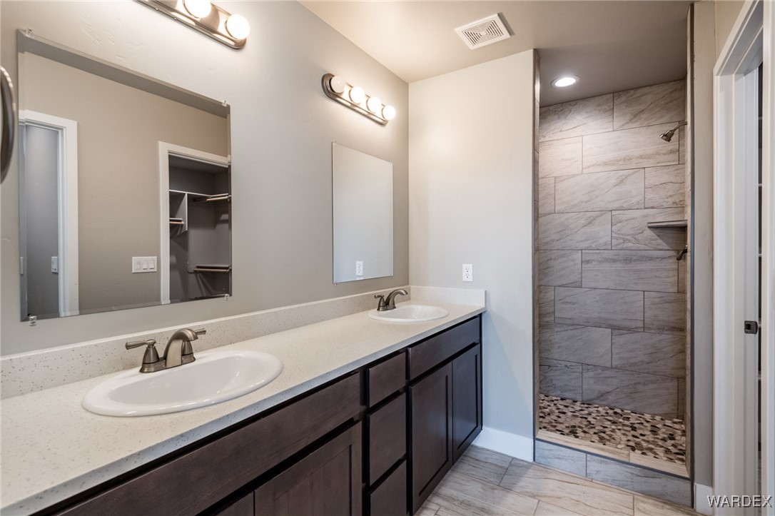 3355 North Bryce Road Golden Valley, AZ 86413 - Photo 10 of 31 a bathroom with a double vanity sink a large mirror and shower