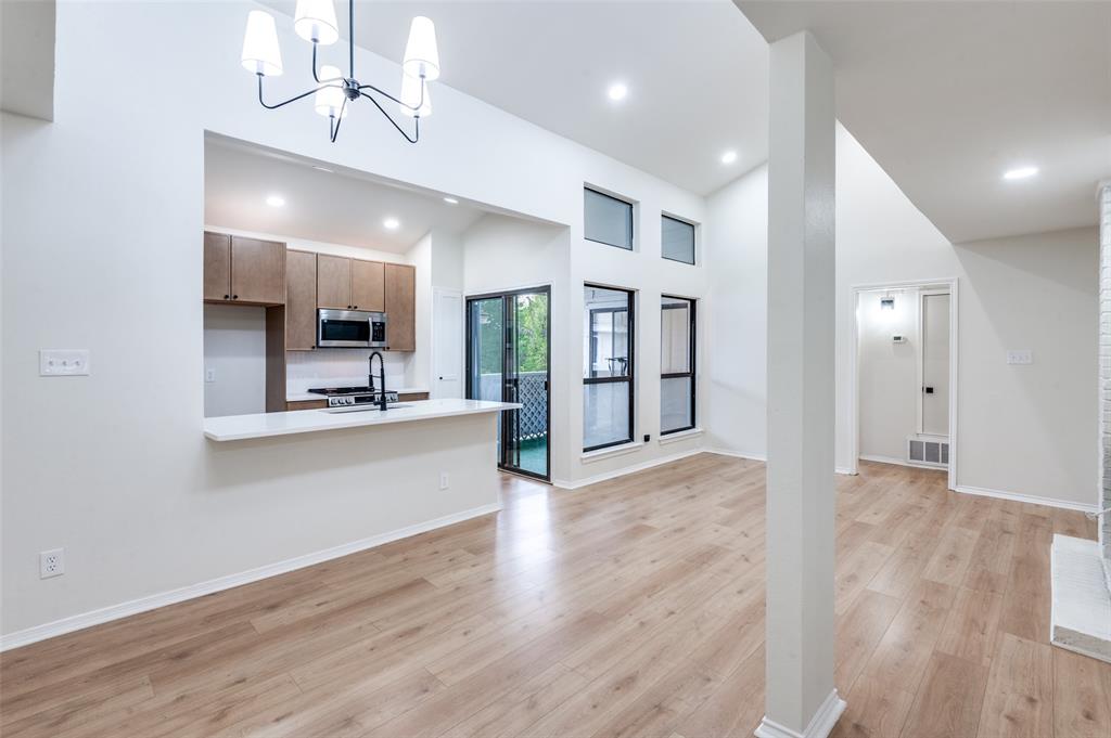 17490 Meandering Way, Unit 2202 Dallas, TX 75252 - Photo 9 of 24 Open-concept living space featuring wood-finish flooring, a contemporary chandelier, and high ceilings