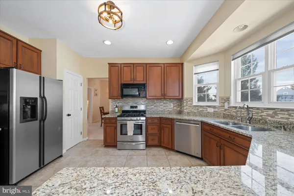 a kitchen with granite countertop stainless steel appliances a sink a counter space and cabinets