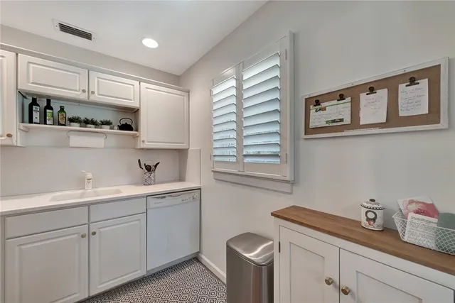 a kitchen with a sink dishwasher window and cabinets