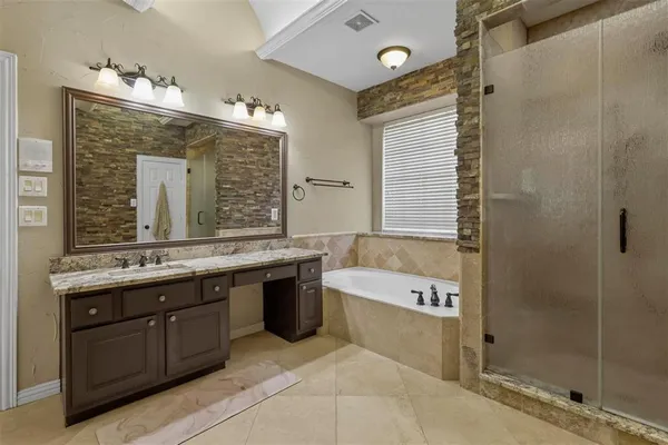 a bathroom with a granite countertop tub sink shower and mirror