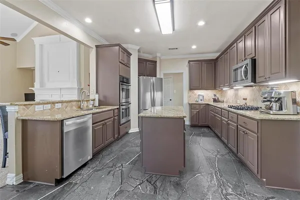 a large kitchen with stainless steel appliances lots of counter space and wooden cabinets