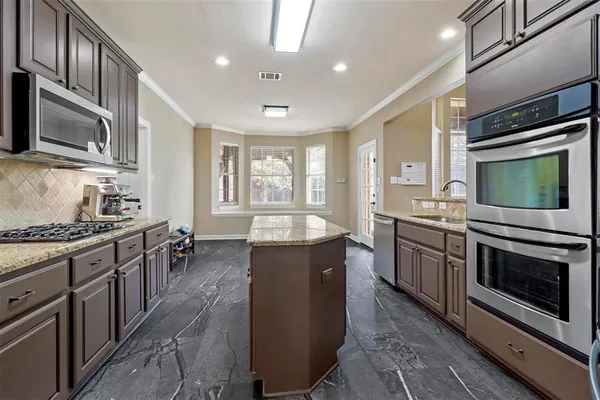 a large kitchen with stainless steel appliances granite countertop a stove top oven a sink dishwasher a dining table and chairs with wooden floor