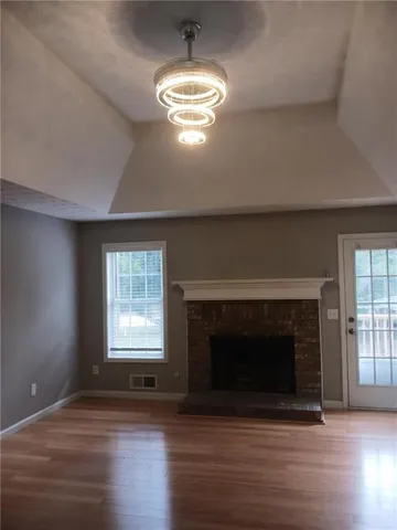 an empty room with wooden floor fireplace and windows