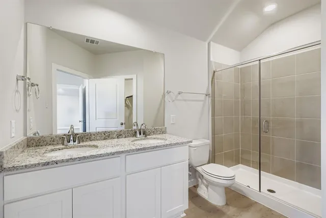 a bathroom with a granite countertop sink a toilet and shower