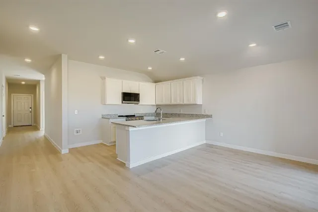 a large kitchen with stainless steel appliances granite countertop a stove a sink and a refrigerator with wooden floor