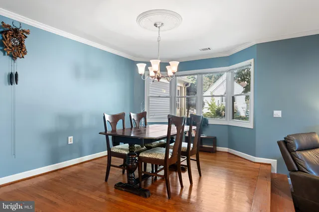 a dining room with furniture a chandelier and wooden floor