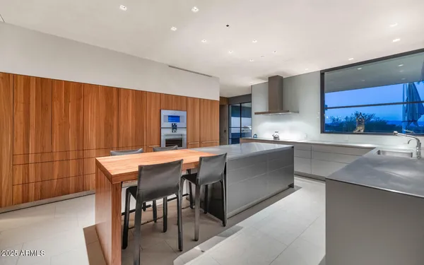 a kitchen with stainless steel appliances granite countertop a table chairs sink and cabinets