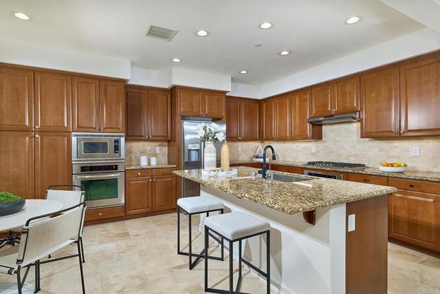 a kitchen with a stove a sink a microwave a refrigerator and chairs