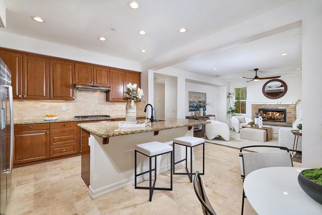 a open kitchen with stainless steel appliances granite countertop a stove top oven a sink a dining table and chairs with wooden floor