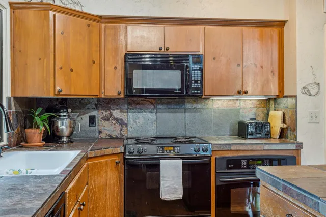 a kitchen with stainless steel appliances granite countertop a stove a sink and a microwave