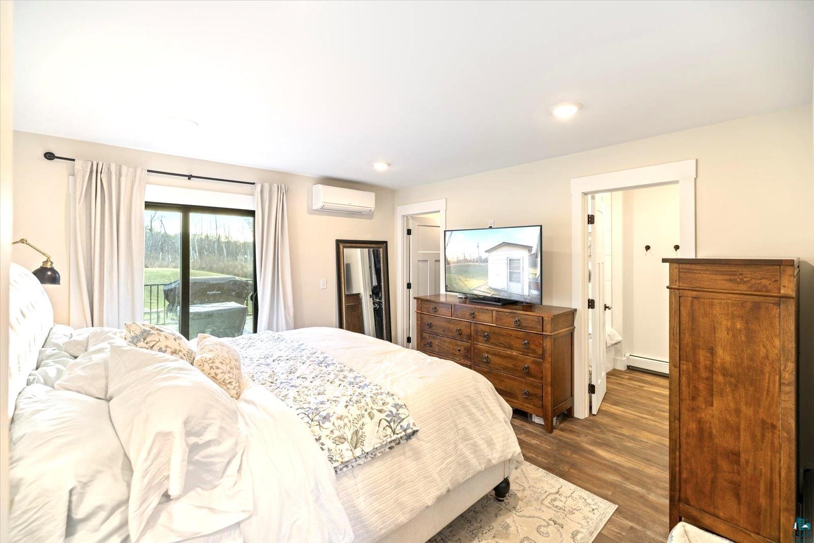 36318 Lakeland Road Sturgeon Lake, MN 55783 - Photo 11 of 23 Bedroom featuring wood finished floors, access to exterior, a wall unit AC, a baseboard radiator, and recessed lighting