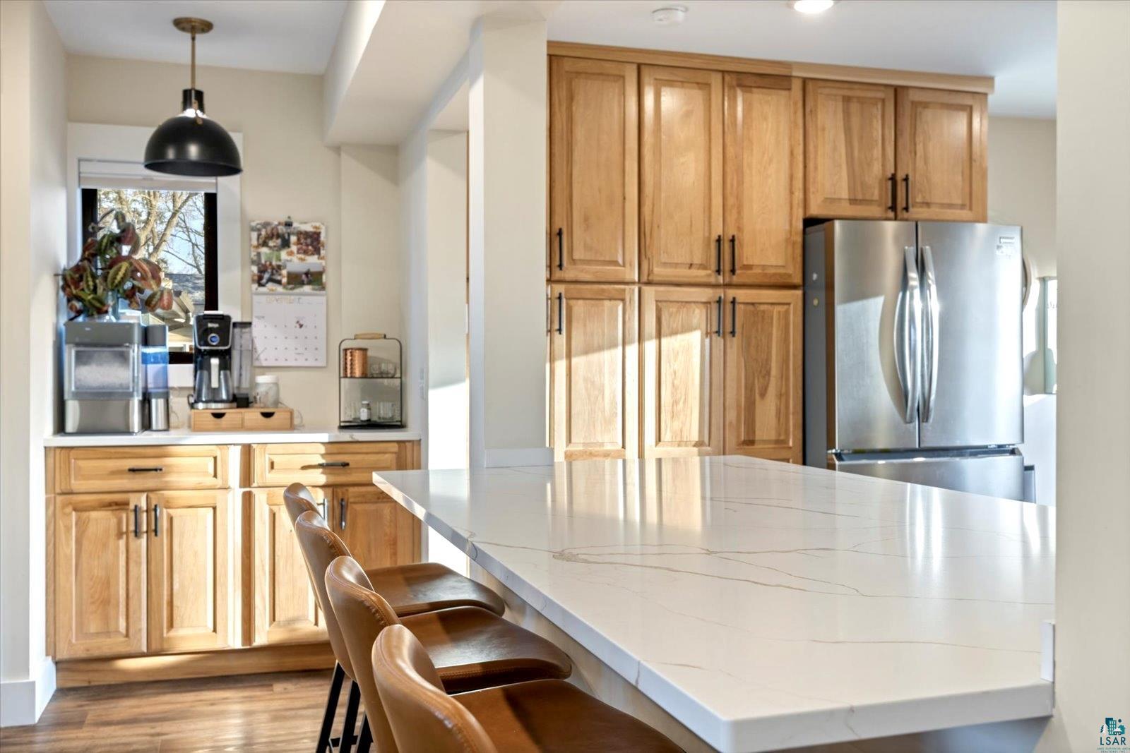 36318 Lakeland Road Sturgeon Lake, MN 55783 - Photo 5 of 23 Kitchen with freestanding refrigerator, pendant lighting, brown cabinets, light wood-type flooring, and light stone counters