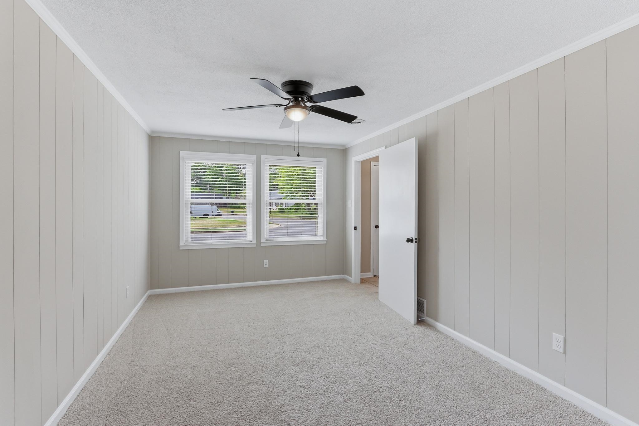 312 Fernway Road Memphis, TN 38117 - Photo 9 of 38 Empty room with ornamental molding, ceiling fan, light carpet, and wood walls